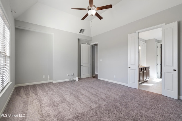 unfurnished bedroom with lofted ceiling, multiple windows, visible vents, and light colored carpet