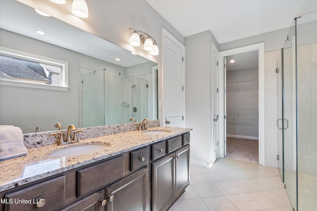 full bath with double vanity, a shower stall, a spacious closet, and a sink