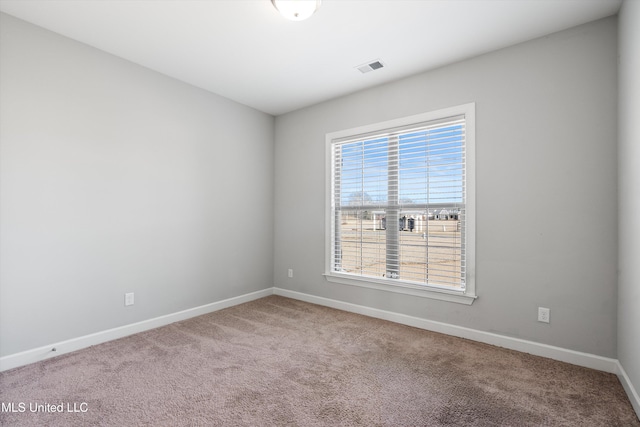 empty room with carpet, visible vents, and baseboards