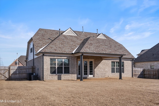 back of property featuring a shingled roof, brick siding, a lawn, and a fenced backyard