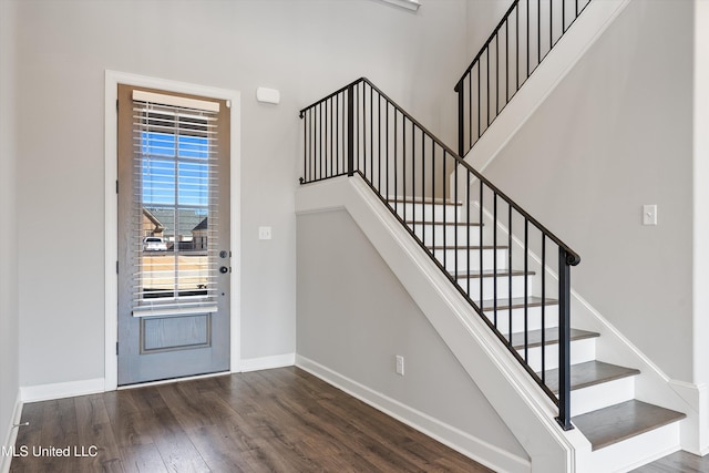 foyer with stairs, a high ceiling, baseboards, and wood finished floors