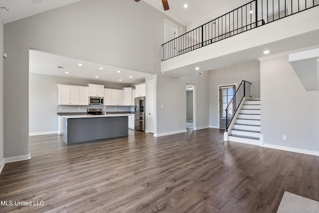 unfurnished living room featuring dark wood-style flooring, ceiling fan, and baseboards