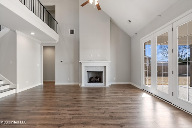 unfurnished living room featuring dark wood-style flooring, a ceiling fan, a high end fireplace, visible vents, and baseboards