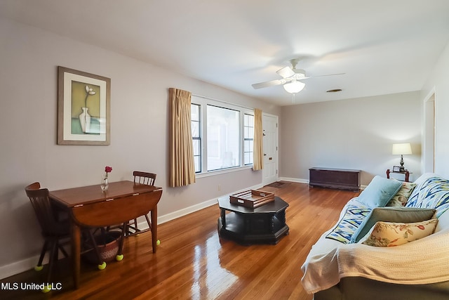 living area featuring wood finished floors, a ceiling fan, and baseboards