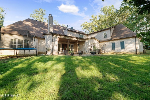1075 S Laughter Rd, Hernando, MS 38632 - back of property with a trampoline, a patio, a lawn, and a chimney