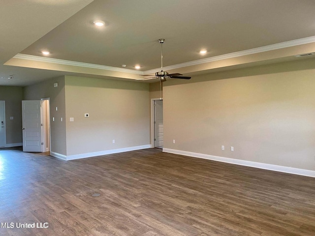 empty room with ornamental molding, dark wood-type flooring, a raised ceiling, and ceiling fan