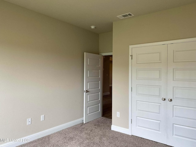 unfurnished bedroom featuring light colored carpet and a closet