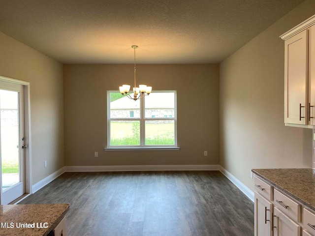 unfurnished dining area with dark wood-type flooring, a chandelier, and plenty of natural light