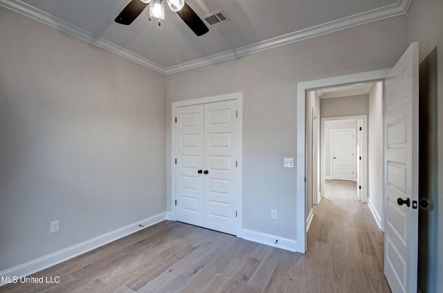 unfurnished bedroom featuring a closet, wood finished floors, visible vents, and crown molding