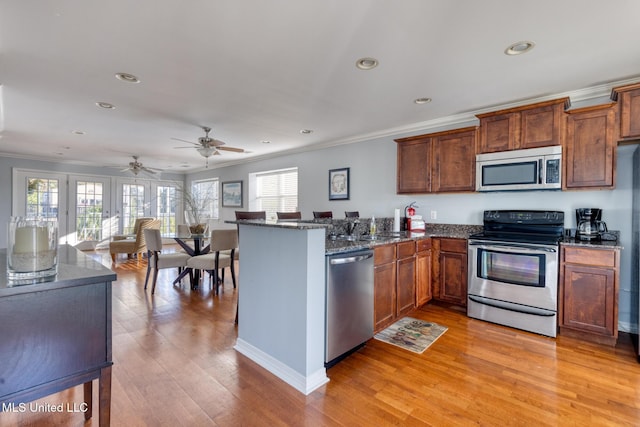 2421 Beachview Dr Unit B02, Ocean Springs, MS 39564 - kitchen with ornamental molding, a peninsula, dark stone counters, light wood finished floors, and stainless steel appliances
