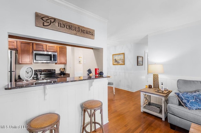 2421 Beachview Dr Unit B02, Ocean Springs, MS 39564 - kitchen featuring ornamental molding, a kitchen bar, brown cabinets, dark stone countertops, and stainless steel appliances