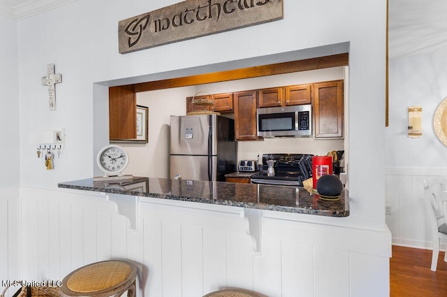 2421 Beachview Dr Unit B02, Ocean Springs, MS 39564 - kitchen featuring stainless steel appliances, dark stone countertops, a wainscoted wall, and a peninsula