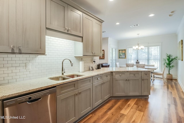 kitchen featuring decorative light fixtures, dishwasher, sink, hardwood / wood-style flooring, and light stone countertops