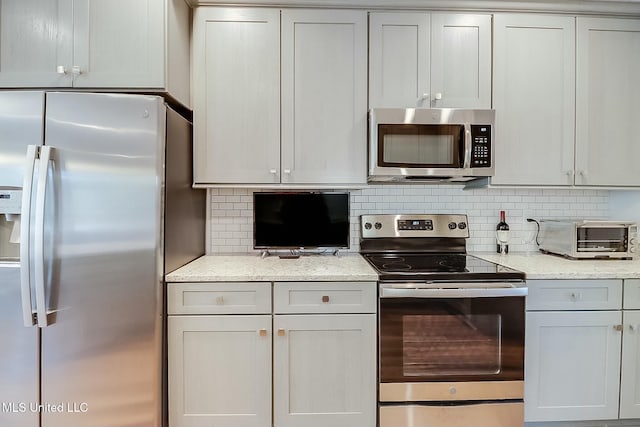 kitchen featuring tasteful backsplash, appliances with stainless steel finishes, and light stone counters