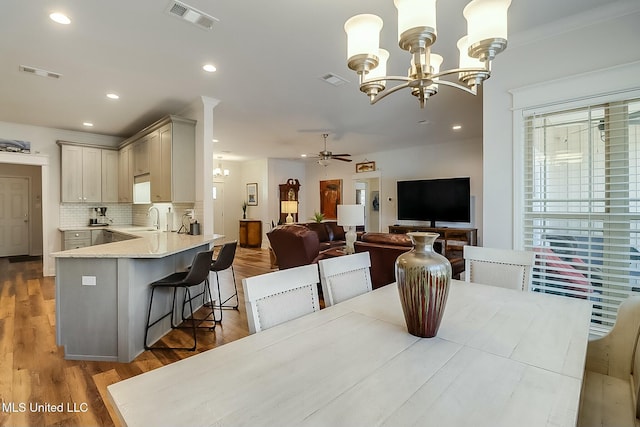 dining space with ceiling fan with notable chandelier, sink, and hardwood / wood-style floors