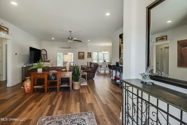 living room featuring hardwood / wood-style flooring, crown molding, and ceiling fan with notable chandelier