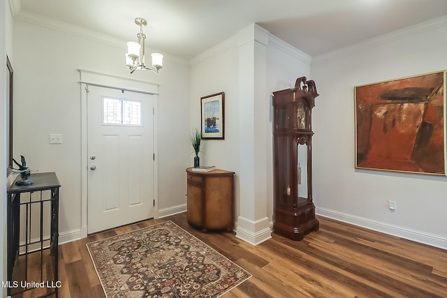 entryway featuring dark wood-type flooring, ornamental molding, and an inviting chandelier