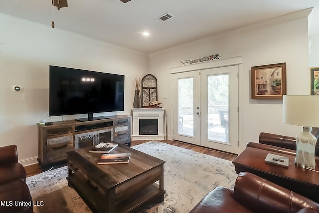 living room featuring hardwood / wood-style flooring, ceiling fan, ornamental molding, and french doors