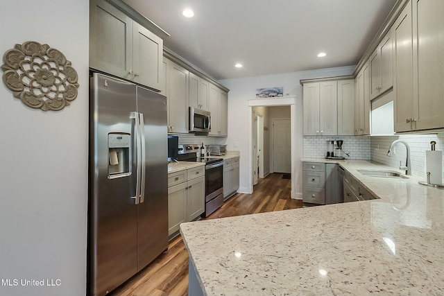 kitchen with stainless steel appliances, light stone countertops, sink, and gray cabinetry