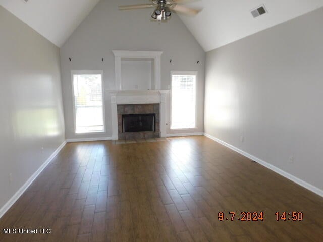 unfurnished living room with dark wood-type flooring, high vaulted ceiling, and a healthy amount of sunlight