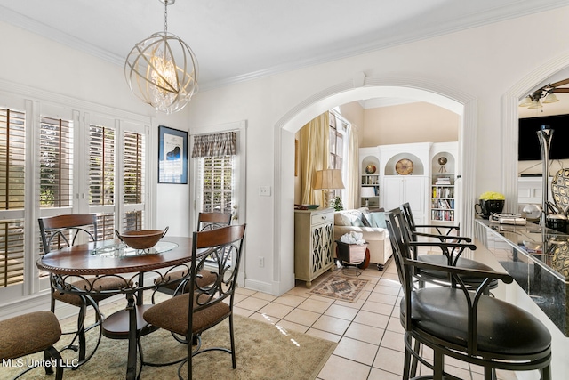 tiled dining room with a healthy amount of sunlight, ornamental molding, ceiling fan with notable chandelier, and built in shelves