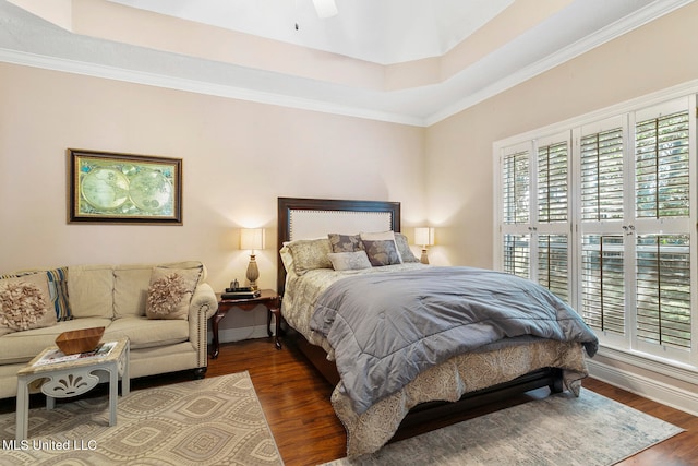 bedroom featuring ornamental molding, dark wood-type flooring, a raised ceiling, and ceiling fan