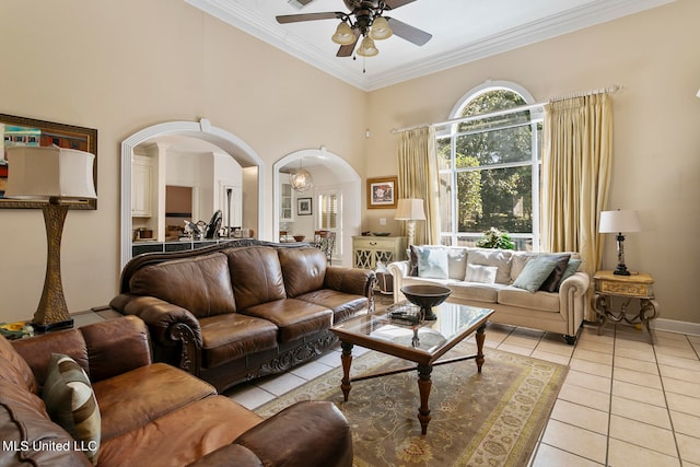 tiled living room featuring ceiling fan, crown molding, and a towering ceiling