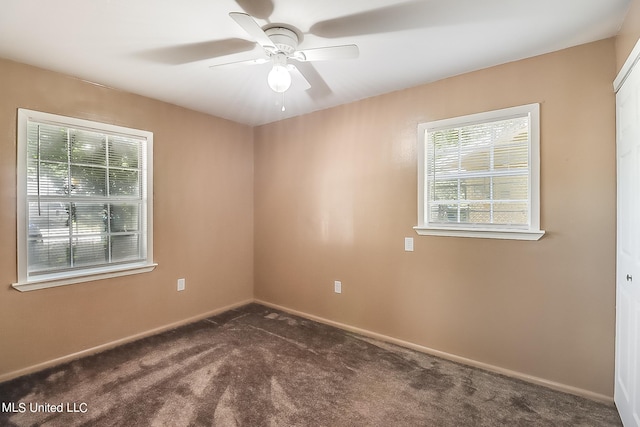 spare room with ceiling fan and dark colored carpet