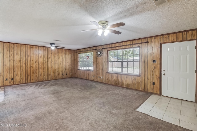 interior space featuring ceiling fan, crown molding, a textured ceiling, and wooden walls