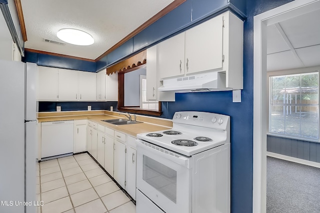 kitchen featuring white appliances, sink, a textured ceiling, white cabinets, and light tile patterned floors