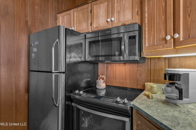 kitchen featuring stainless steel appliances and wood walls