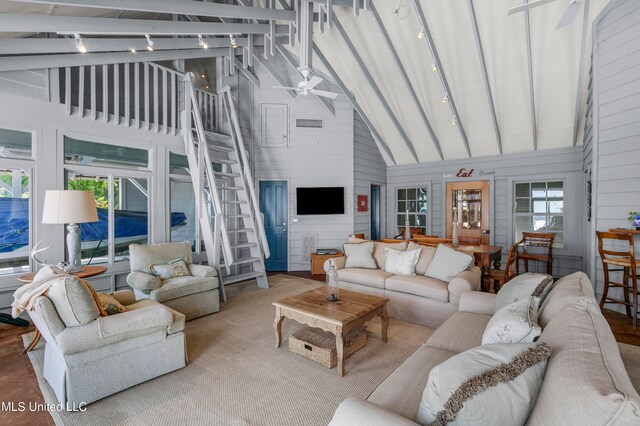 living room featuring track lighting, beamed ceiling, wooden walls, high vaulted ceiling, and ceiling fan