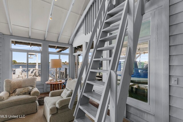 stairway with vaulted ceiling, a wealth of natural light, and wooden walls