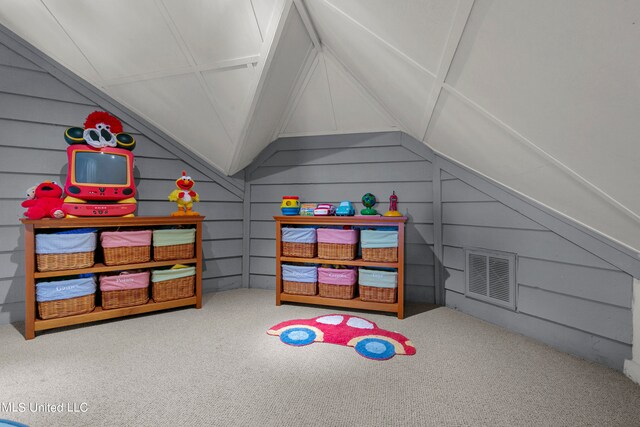 recreation room featuring wooden walls, carpet, and vaulted ceiling