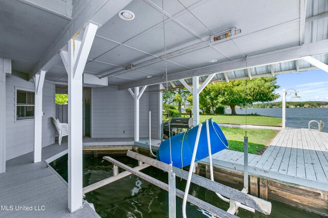 dock area with a lawn and a water view