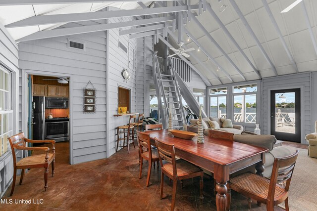 dining area with beamed ceiling, ceiling fan, and wood walls