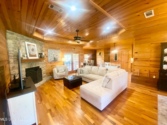 living room featuring a fireplace, light hardwood / wood-style floors, ceiling fan, wooden ceiling, and wooden walls