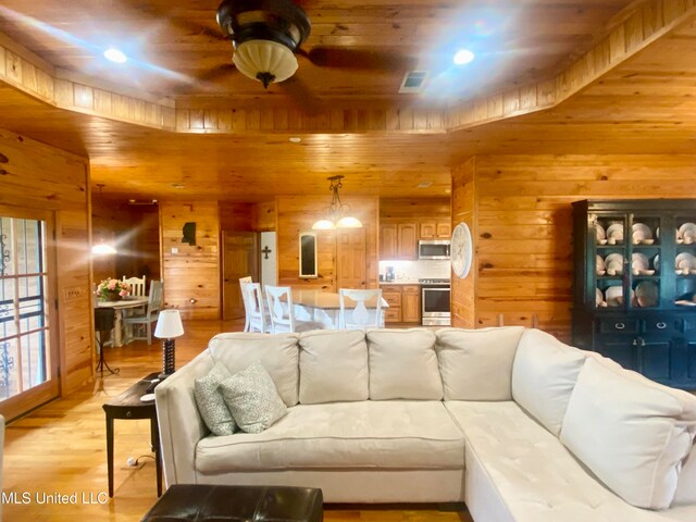 living room with ceiling fan, wood walls, light hardwood / wood-style flooring, and wood ceiling