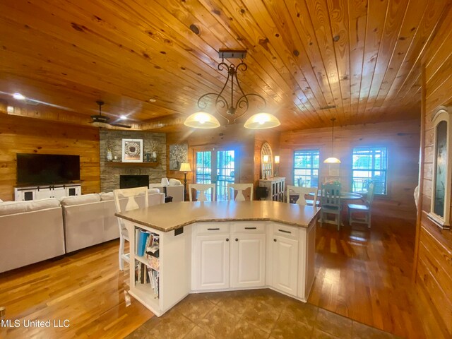 kitchen with wooden walls, white cabinetry, decorative light fixtures, and a kitchen island