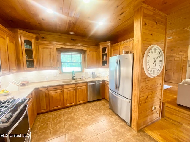 kitchen with stainless steel appliances, backsplash, wooden ceiling, sink, and wood walls