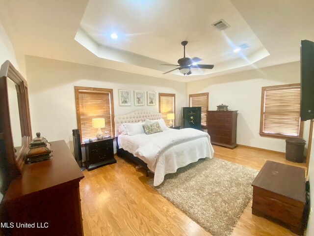 bedroom featuring a raised ceiling, light hardwood / wood-style flooring, and ceiling fan