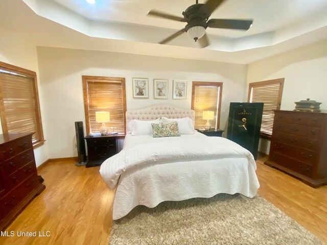 bedroom featuring a tray ceiling, light hardwood / wood-style floors, and ceiling fan