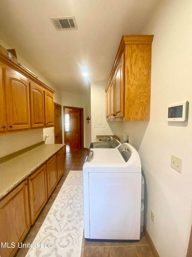 laundry room featuring cabinets, washer and clothes dryer, and dark tile patterned flooring