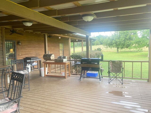 wooden terrace featuring area for grilling, ceiling fan, and a lawn