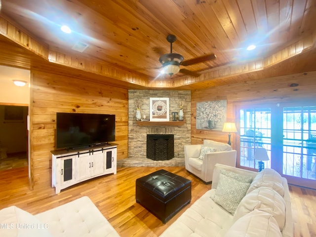 living room with ceiling fan, wood walls, a fireplace, and hardwood / wood-style floors