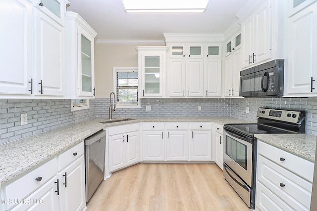 kitchen with backsplash, appliances with stainless steel finishes, white cabinetry, ornamental molding, and light hardwood / wood-style floors