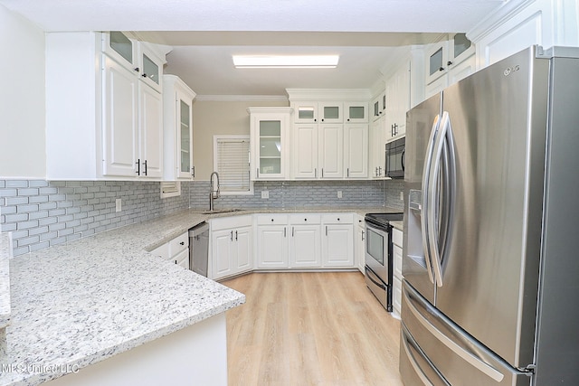 kitchen with decorative backsplash, sink, white cabinets, appliances with stainless steel finishes, and light hardwood / wood-style floors