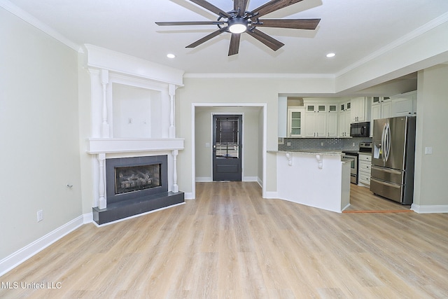 kitchen with appliances with stainless steel finishes, crown molding, and light hardwood / wood-style floors