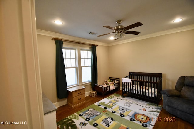 bedroom featuring ceiling fan, ornamental molding, and a crib