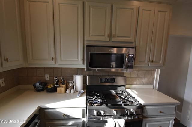 kitchen with decorative backsplash, cream cabinets, and appliances with stainless steel finishes